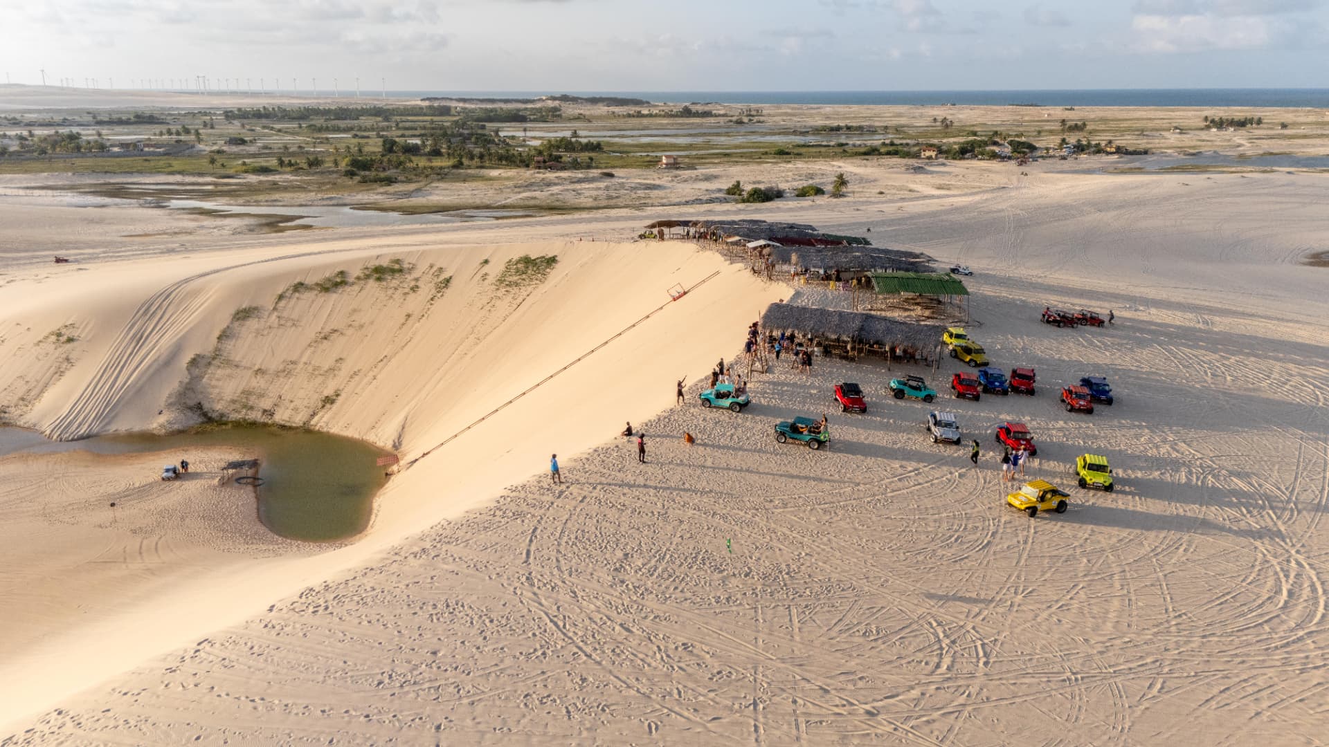 Duna com lagoa e barracas durante roteiro de buggy
