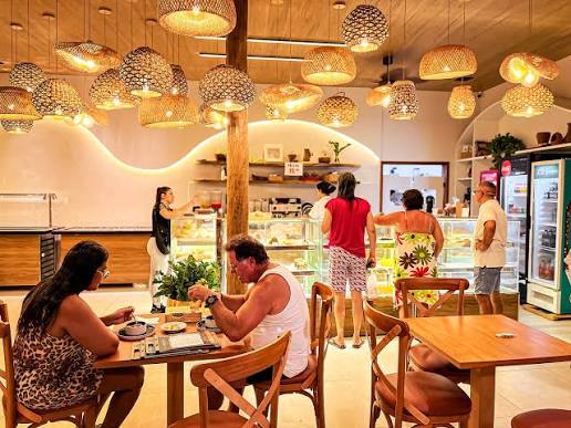 Salão interno da padaria com luminárias de palha e vitrines